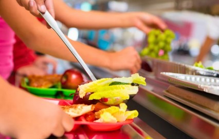 A cafeteria with kids serving themselves food on colorful trays